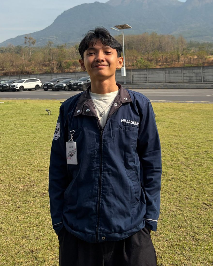 Foto Azzam Syaiful Islam mengenakan jaket himpunan, dengan latar pegunungan.
